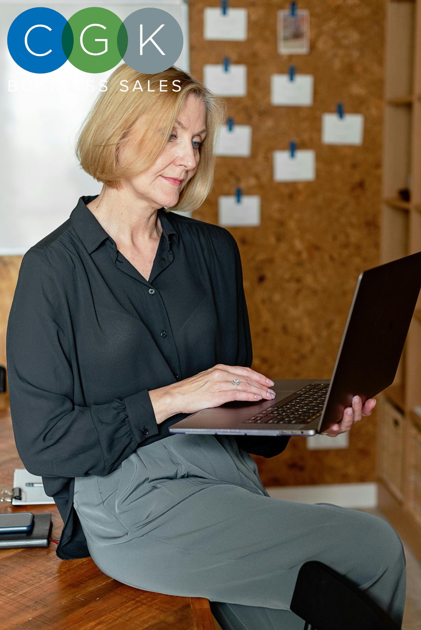 Experienced business advisor working on a laptop, highlighting CGK Business Sales' expertise in selling businesses efficiently and profitably.